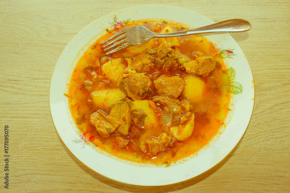 Tasty winter stew with meat and vegetables in bowl with ingredie Tasty winter stew with meat and vegetables in bowl with ingredie