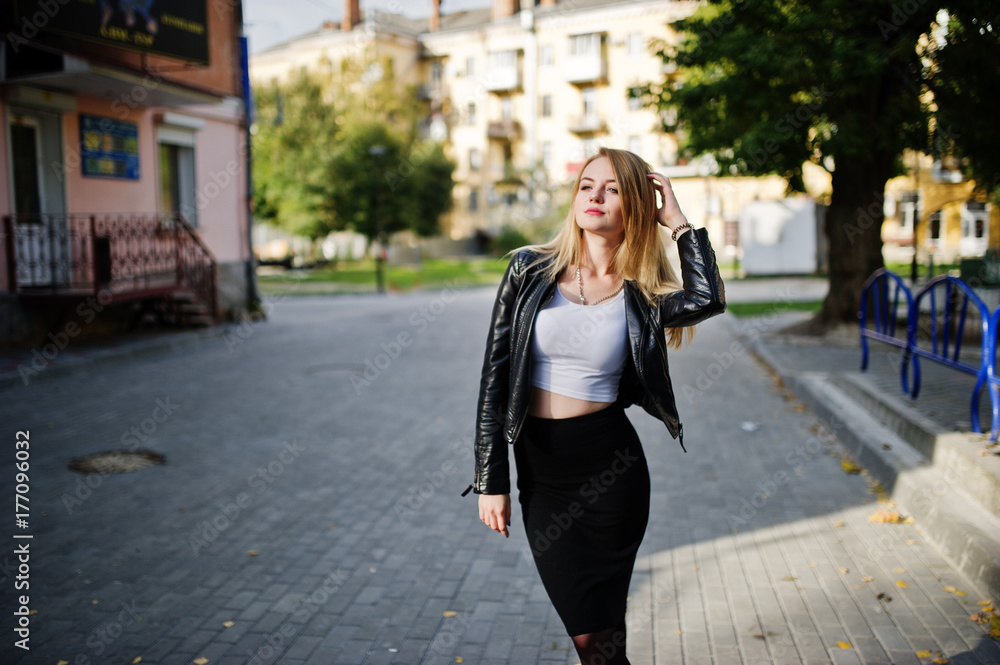 Elegant blonde girl wear on black leather jacket posing at streets of town.