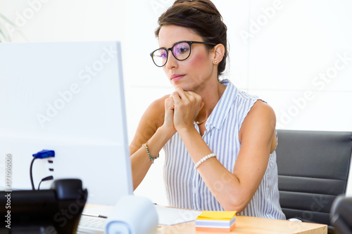 Beautiful young businesswoman working with laptop in modern office. photo