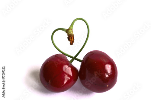 Closeup of cherries with a heart shaped stem on a white background
