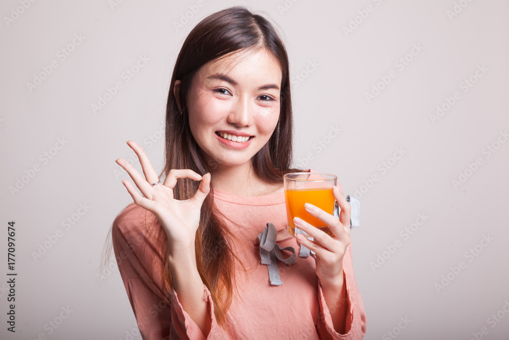 Young Asian woman drink orange juice show OK sign. Young Asian woman drink orange juice show OK sign.