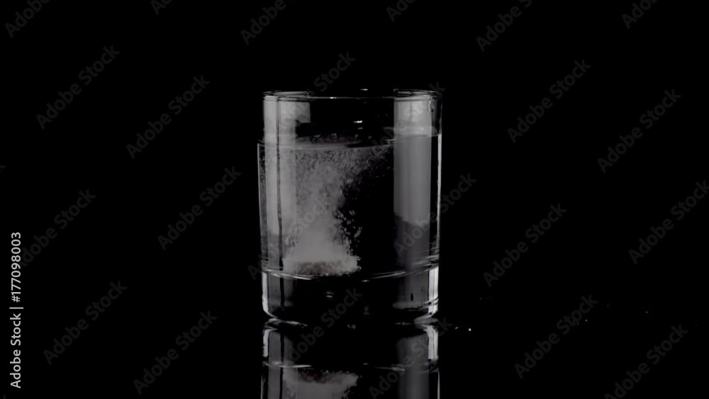 Effervescent tablet falling in a glass of water on black background. Taking medication concept. Taking calcium, magnesium, vitamins, aspirin for a healthy life. 4k Effervescent tablet falling in a glass of water on black background. Taking medication concept. Taking calcium, magnesium, vitamins, aspirin for a healthy life. 4k