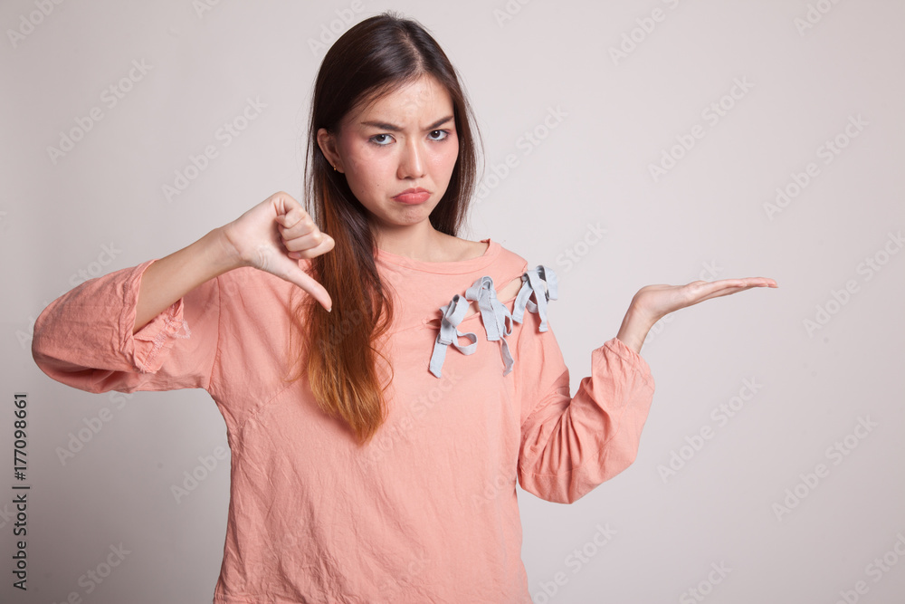Young Asian woman show palm hand and thumbs down. Young Asian woman show palm hand and thumbs down.