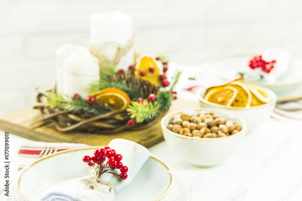 a table setting for Christmas with a viburnum on a plate and an ornament from a Christmas wreath with candles