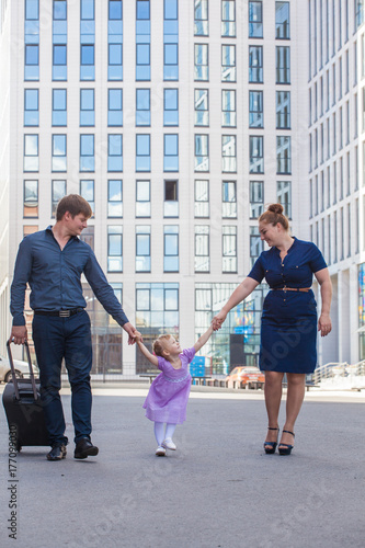 Family with a suitcase in the background of a tall building. The family is moving. © izida1991