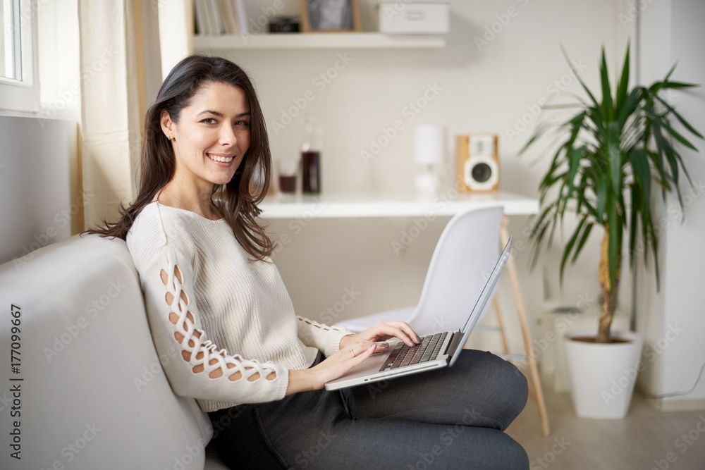 Freelancer using laptop for searching internet while sitting on sofa in living room Freelancer using laptop for searching internet while sitting on sofa in living room