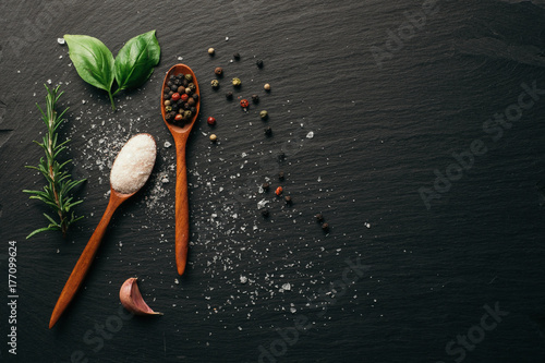 Sea salt and mixed peppercorn on dark black slate board. Top view. Copy space. 
