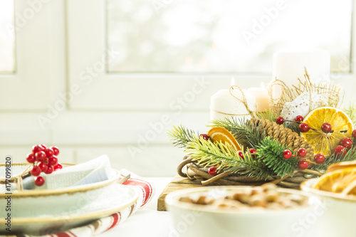 a table setting for Christmas with a viburnum on a plate and an ornament from a Christmas wreath with candles
