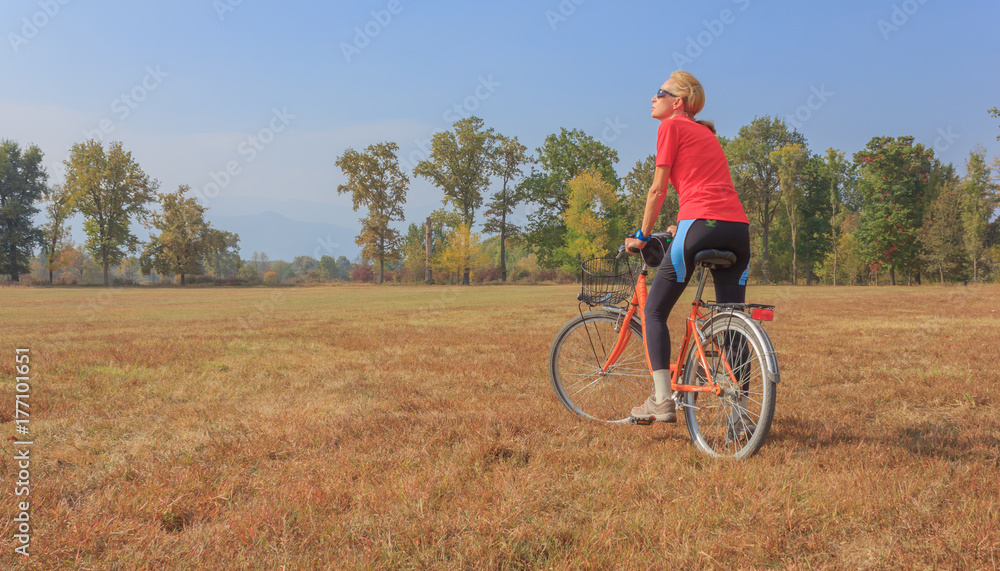 a woman exercises on a bicycle / a healthy lifestyle of a fifty-years-old woman practicing cycling in a park