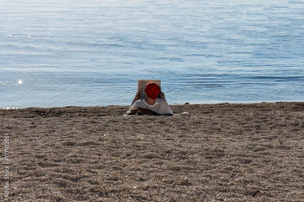 Young woman enjoying time at the beach, reading newspaper Young woman enjoying time at the beach, reading newspaper