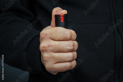 Hand with bottle of pepper spray. photo