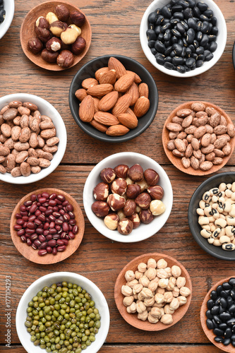 Assortment of beans and lentils in wooden spoon on teak wood background