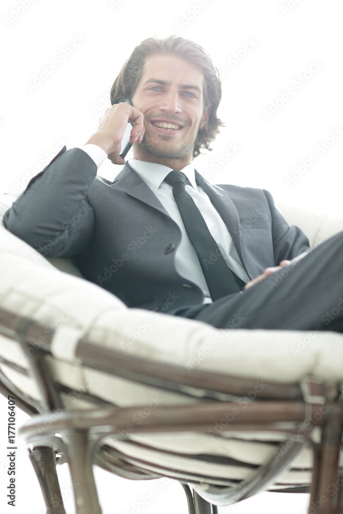 business man talking on a smartphone while sitting in a comfortable chair. business man talking on a smartphone while sitting in a comfortable chair.