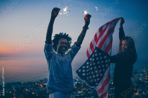 Couple celebrating with sparkler and USA flag at night photo