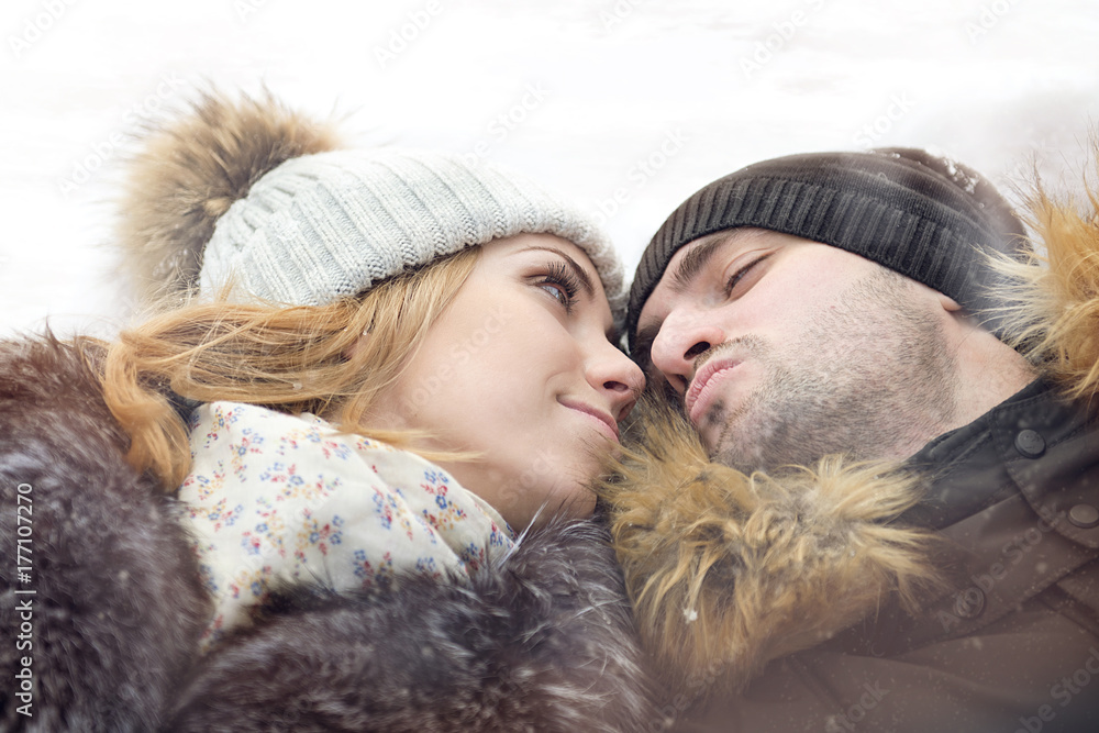 A man and a woman on the verge of a kiss lying in the snow close-up A man and a woman on the verge of a kiss lying in the snow close-up