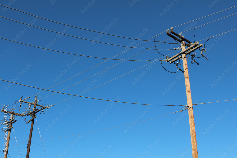 Terminal end of power poles with blue sky behind
