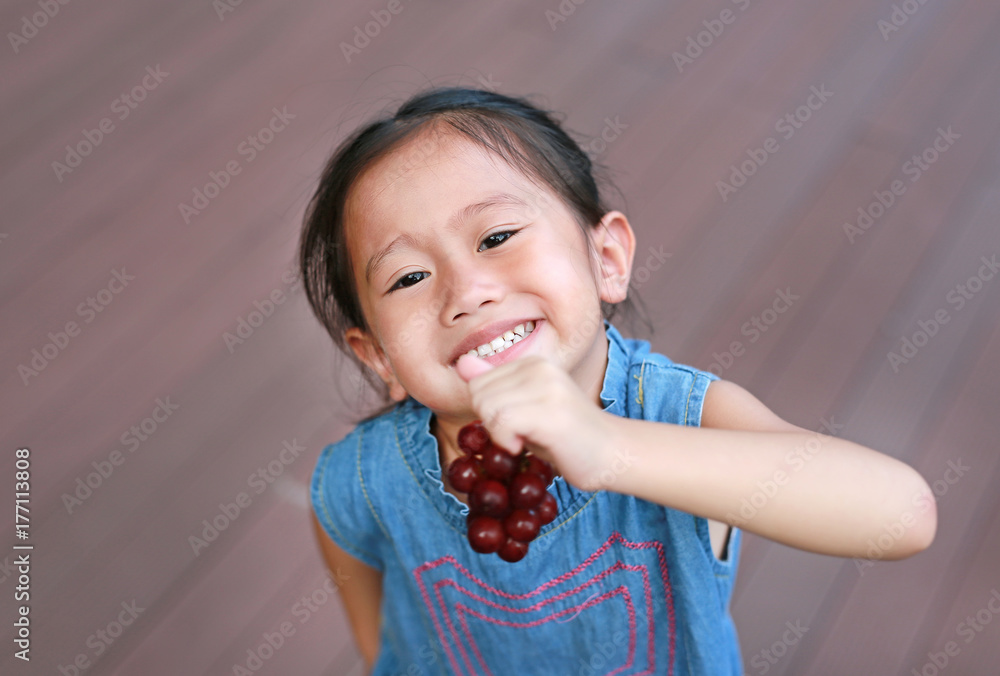 Little girl eating Purple grape fruit in the garden. Little girl eating Purple grape fruit in the garden.