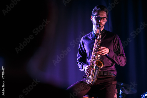 Saxophonist playing on a stage. Pink and blue lighning. Black background
