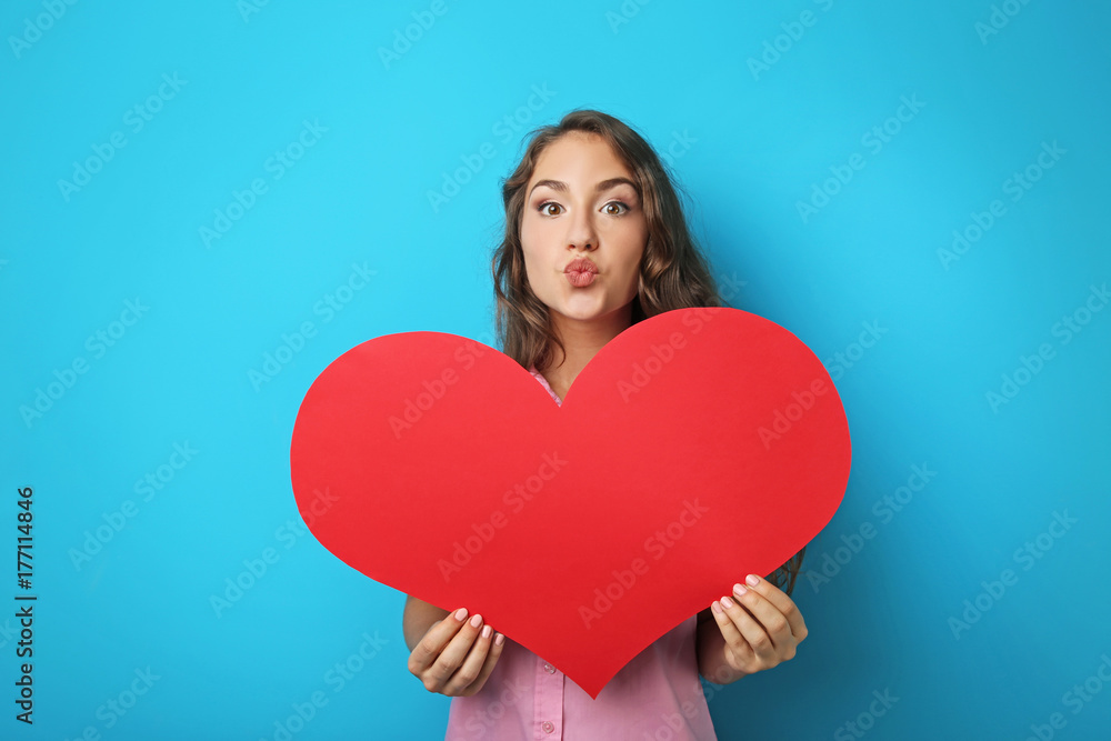 Portrait of young woman holding red heart on blue background Portrait of young woman holding red heart on blue background