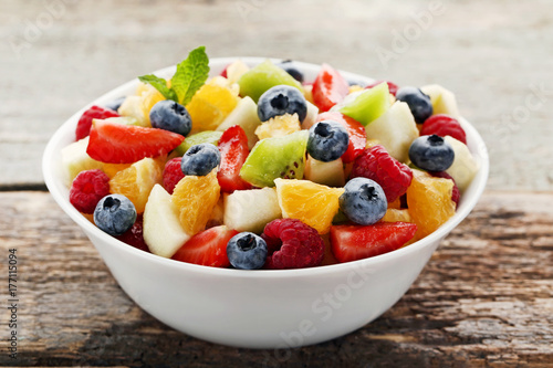 Fresh fruit salad in bowl on grey wooden table