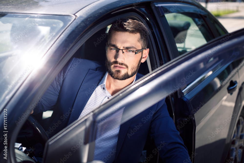 Handsome young man coming out of the car