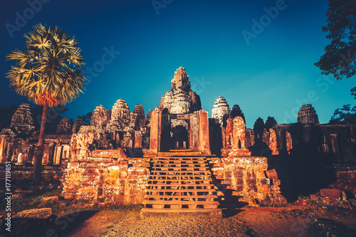 Angkor Wat Temple in Cambodia is the largest religious complex  inscribed on UNESCO World Heritage List. Ancient Khmer architecture. Orange ancient ruins against blue night sky. Retro vintage toning
