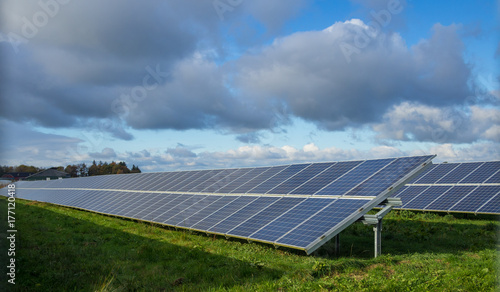 Solar panel or photovoltaic farm on green field with dramatic cloudy sky in North Germany