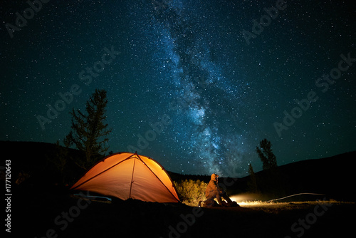 Man tourist near his camp tent at night.
