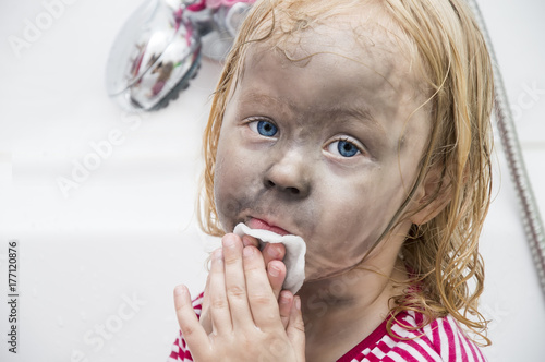 little girl went too far with make-up, first make-up. washing in the bathroom photo