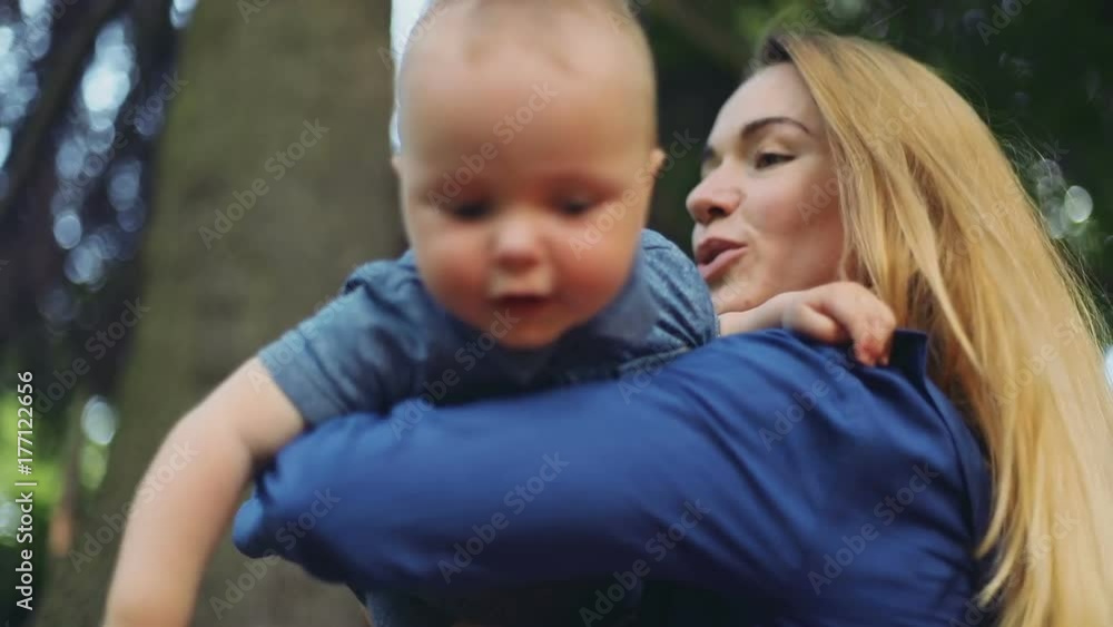 closeup adorable little baby boy mother hands holding green park looking camera interested look eyes happy emotions face portrait chubby cheeks throwing up funny playing sunny day smiling cheerful closeup adorable little baby boy mother hands holding green park looking camera interested look eyes happy emotions face portrait chubby cheeks throwing up funny playing sunny day smiling cheerful
