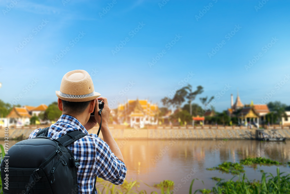 Traveling asia,leisure travel concept.Hipster tourist wandering  and taking a picture of the historical temple beside a river in Ayutthaya province at sunset and twilight blue sky.