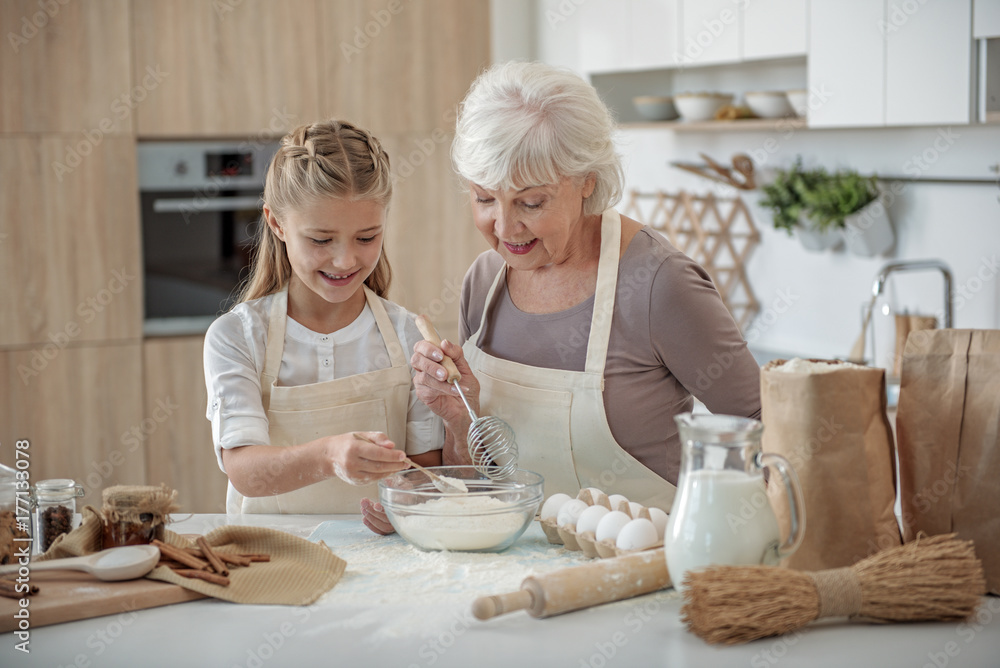 Happy granddaughter mixing flour with egg in kitchen Happy granddaughter mixing flour with egg in kitchen