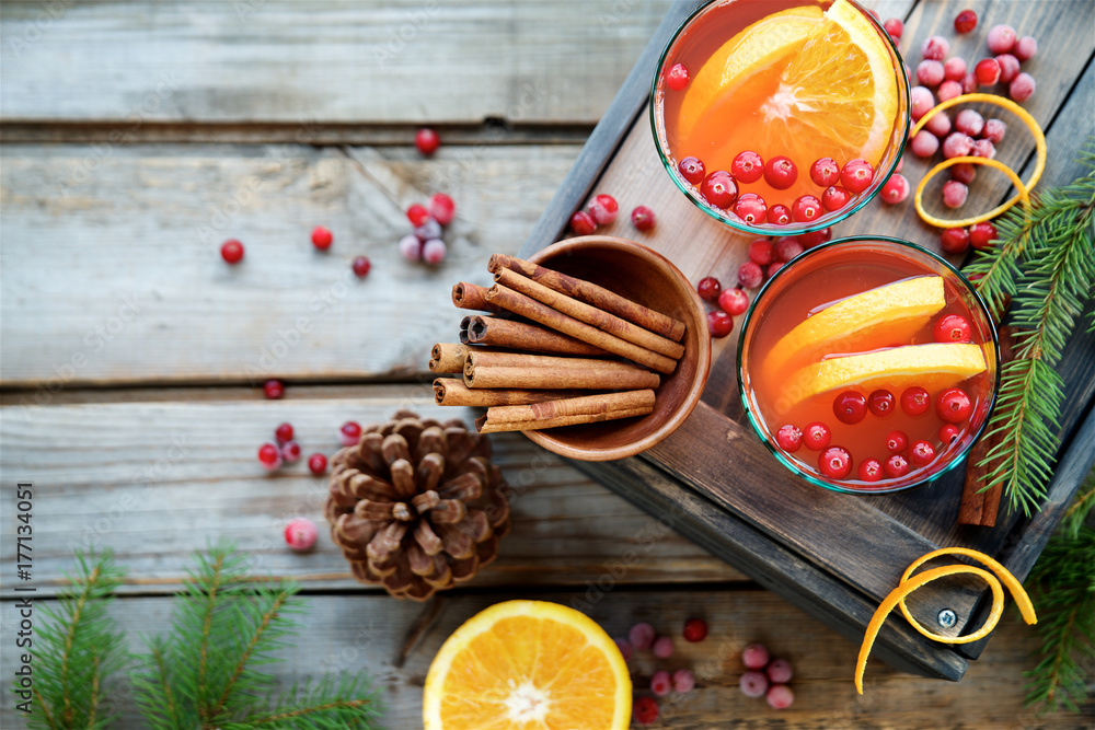 Warm cranberry drink with oranges and cinnamon. Wooden background, top view 
