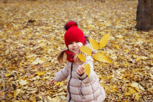 child knit hat fur pompon walking on fallen leaves