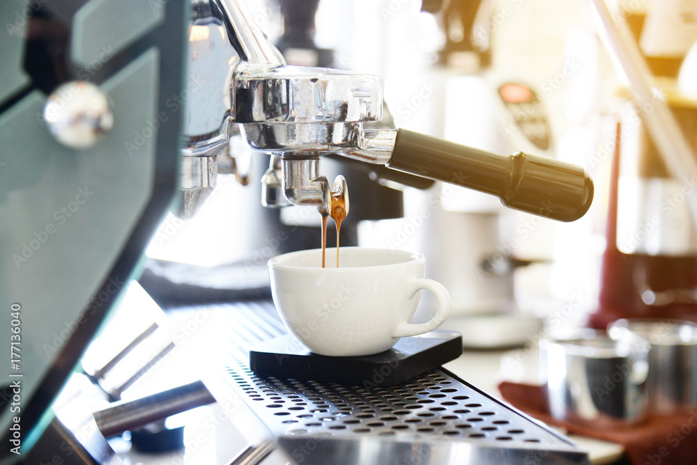 coffee machine pouring coffee into white coffee cup.Cappuccino pouring from professional coffee machine brewing coffee machine pouring coffee into white coffee cup.Cappuccino pouring from professional coffee machine brewing