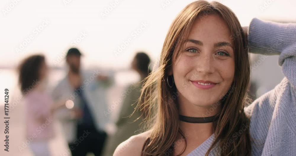 Young brown haired woman smiling with friends in the background Young brown haired woman smiling with friends in the background