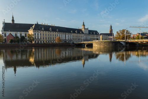 Buildings of the University Church of the Blessed Name of Jesus and the University of Wroclaw, and the University Bridge, with reflections in the Odra river at dawn, Wroclaw, Poland