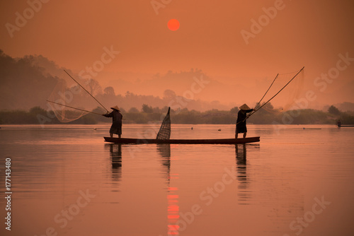 Two fishermen are fishing on the boat at Mekong river in the morning in Nong Khai, Thailand