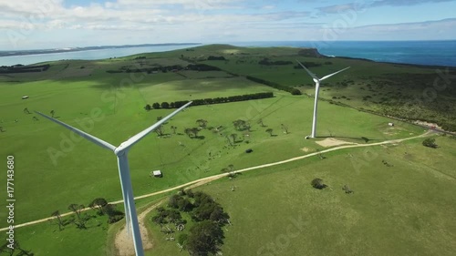 Smooth cinematic flight panning through working wind turbines in Australian countryside