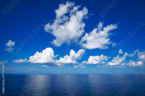 Blue sky with white clouds reflex on the sea.