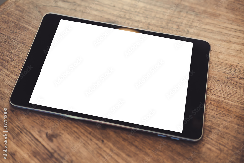 Mockup image of black tablet pc with blank white screen on vintage wooden table background Mockup image of black tablet pc with blank white screen on vintage wooden table background