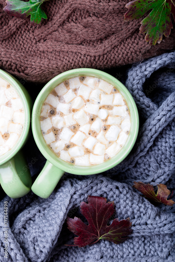 Two cup of coffee or hot chocolate with marshmallow near three knitted grey, black and brown sweater or knitted blanket. Autumn concept. Christmas. Top view. Warm at home. Two cup of coffee or hot chocolate with marshmallow near three knitted grey, black and brown sweater or knitted blanket. Autumn concept. Christmas. Top view. Warm at home.