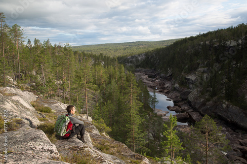 Young hiker sitting at a rocky canyon near by Porjus, Sweden, summer 