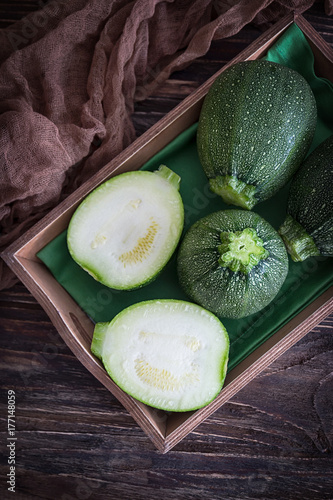 Green round zucchini on a dark wooden background. Rustic style, top view