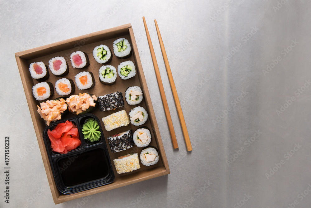 Top view set of sushi maki and rolls with chopstics, rice, soy, wasabi and ginger on grey background Top view set of sushi maki and rolls with chopstics, rice, soy, wasabi and ginger on grey background