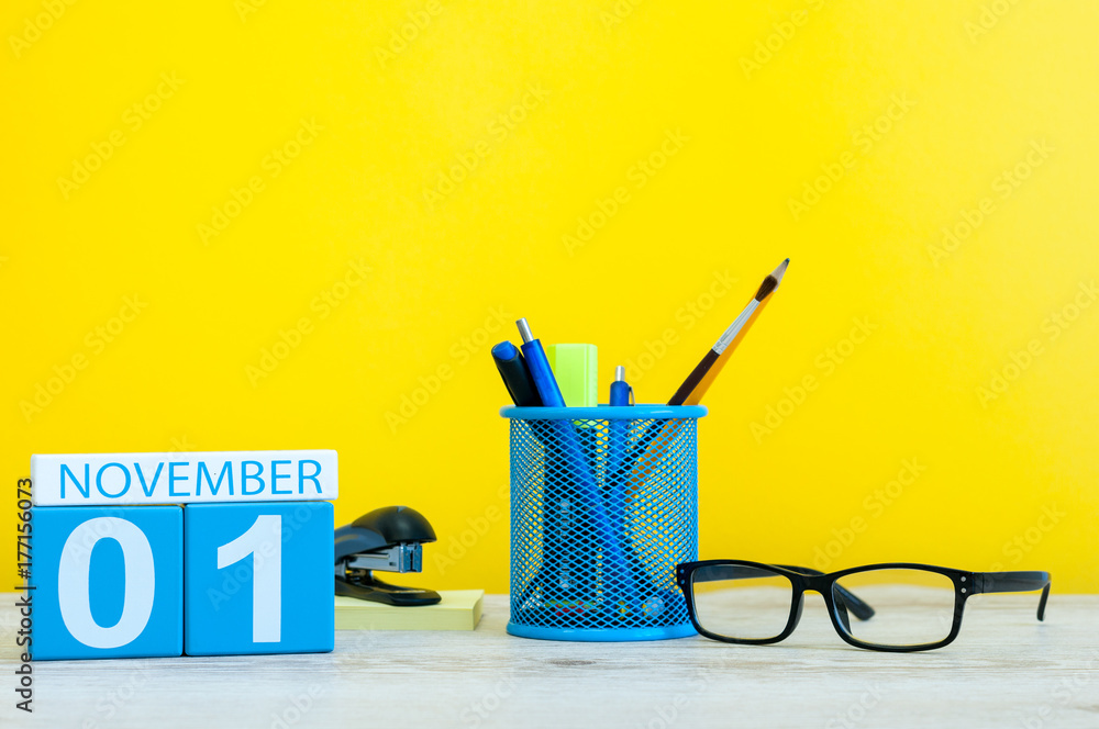 November 1st. Day 1 of month, wooden color calendar on yellow background with office supplies. Autumn time November 1st. Day 1 of month, wooden color calendar on yellow background with office supplies. Autumn time