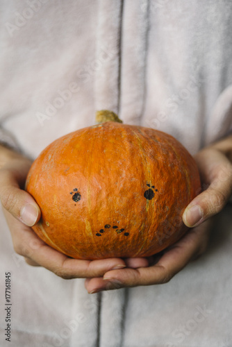 Small Hokkaido pumpkin with a sad face in women's  hand