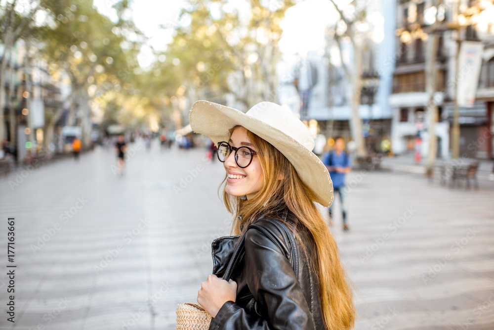 Fototapeta premium Young woman tourist in hat walking on the famous pedestrian boulevard in Barcelona city