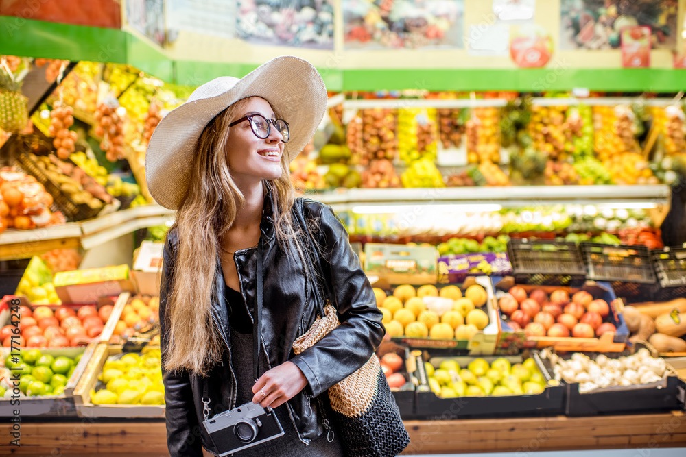Woman standing in front of the food store showcase with fruits and vegetables Woman standing in front of the food store showcase with fruits and vegetables