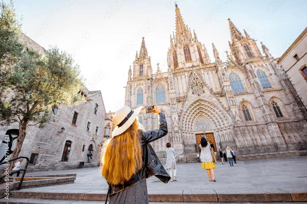 Young woman tourist photographing with phone famous saint Eulalia church during the morning light in Barcelona city - obrazy, fototapety, plakaty 
